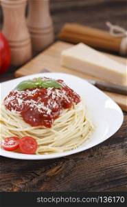 Warm, delicious spaghetti with sauce and basil.. Warm, delicious spaghetti with sauce and basil on wooden table.