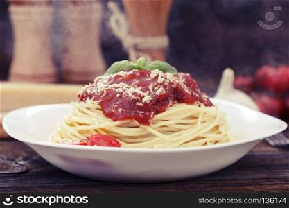 Warm, delicious spaghetti with sauce and basil.. Warm, delicious spaghetti with sauce and basil on wooden table.