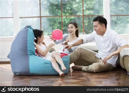 Warm family of three playing with a balloon
