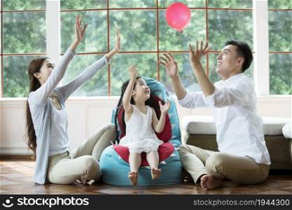 Warm family of three playing with a balloon