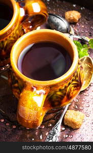 Warm herbal tea. Clay cup with herbal tea on a vintage background