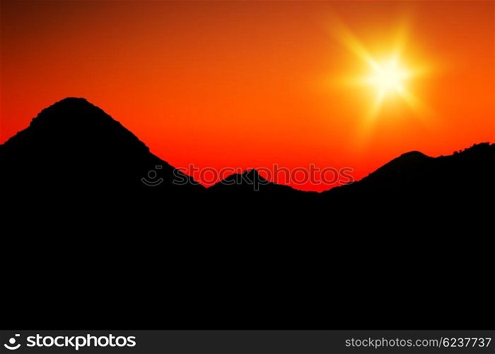 Warm mountains sunset with orange sky &amp; silhouette of mountains