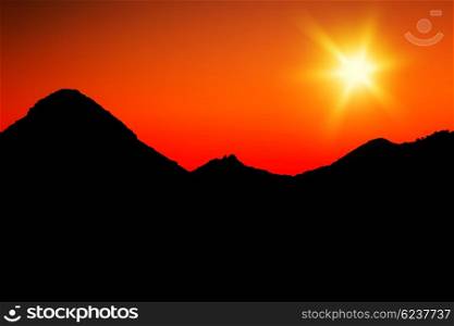 Warm mountains sunset with orange sky &amp; silhouette of mountains