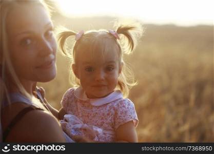 warm portrait of mother and daughter in country style in the field