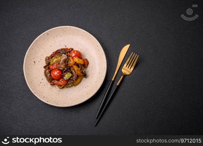 Warm salad with veal, tomatoes, peppers, zucχni, sesame, sa<, sπces and herbs on a dark concrete background