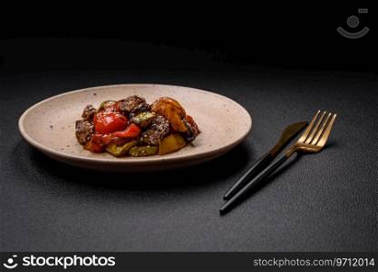 Warm salad with veal, tomatoes, peppers, zucchini, sesame, salt, spices and herbs on a dark concrete background