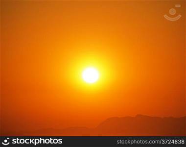 Warm summer sunset at clear sky and distant land shape.