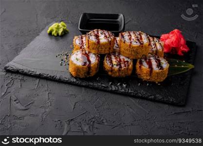 Warm sushi with ginger and wasabi served on a black stone plate