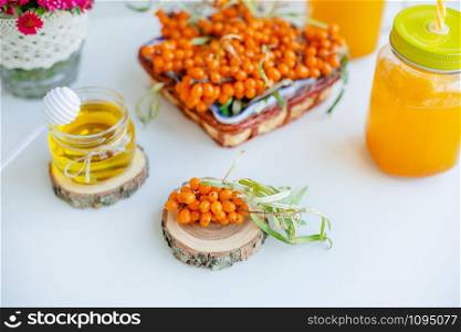 Warm sweet organic tea with sea buckthorn berries, thyme and honey. White background, natural lighting. Horizontal composition with copy space. Concept of beauty in simplicity.. White background, natural lighting. Warm sweet organic tea with sea buckthorn.