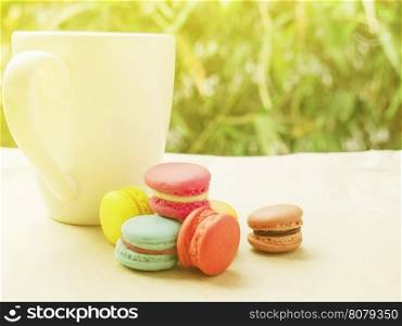 Warm tone of macaroon with coffee cup with warm sunlight, selective focused.