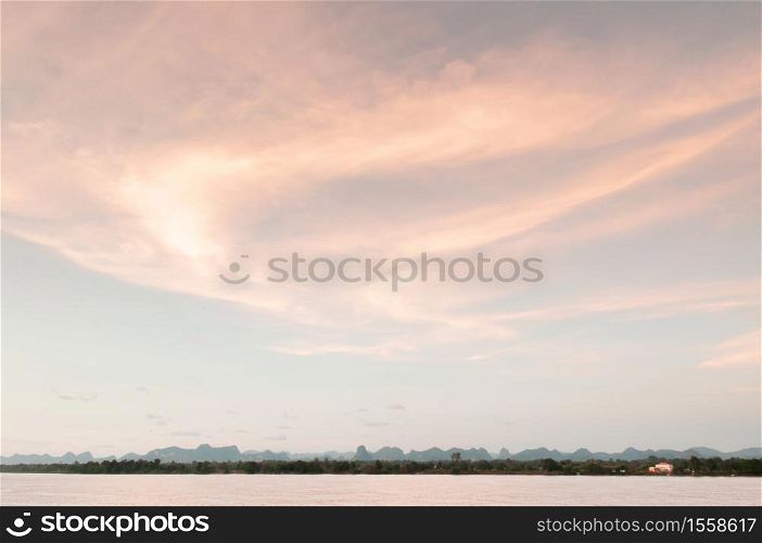 Warm tone sunset sky over Mae Khong river in Nakhon Phanom. Natural border between Thailand and Laos. Peaceful twilight scenery