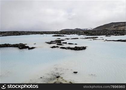 warm water in blue lagoon iceland with mountains with snow as background