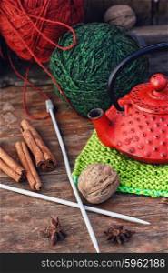 Warm winter tea. Red and green ball of wool for knitting and stylish red kettle.