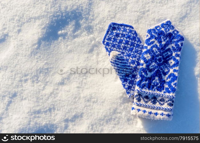 warm woolen mittens with beautiful pattern lying in the snow