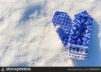 warm woolen mittens with beautiful pattern lying in the snow
