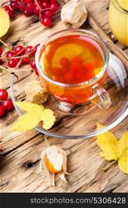 warming autumn tea. cup of berry tea with a mulberry on background with autumn leaves