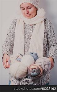 Warmly dressed woman holding a basket of balls woolen yarn. Woman with basket of balls woolen yarn