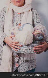 Warmly dressed woman holding a basket of balls woolen yarn. Woman with basket of balls woolen yarn