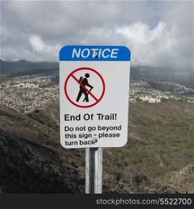 Warning sign for hikers with a city in background viewed from Diamond Head, Kapahulu, Honolulu, Oahu, Hawaii, USA