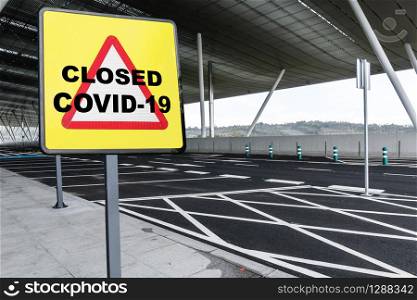 Warning sign with text CLOSED COVID-19 on a empty parking lot of an airport or train station. Coronavirus crisis concept