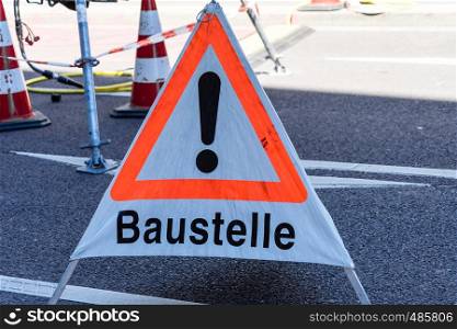 "Warning sign with the German inscription "Achtung, Baustelle" (caution, construction site) on an asphalted road, also notice for unfinished website, concept"