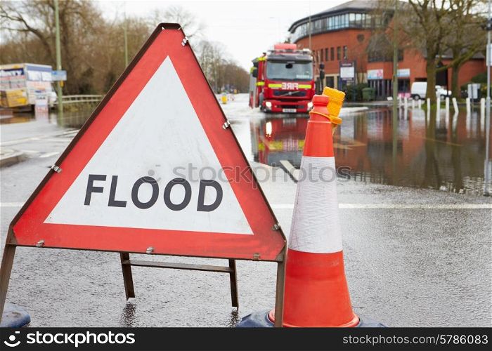 Warning Traffic Sign On Flooded Road With Fire Engine