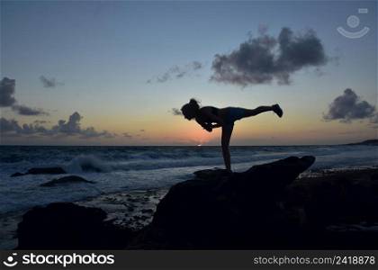 Warrior 3 balance pose silhouetted along the coastline of Aruba.