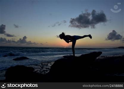 Warrior 3 yoga balance pose with sun rising over the ocean.