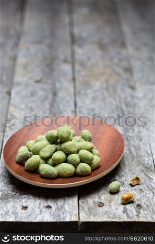 Wasabi peanuts on rustic wooden background.. Wasabi peanuts on rustic wooden background