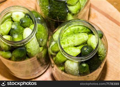 washed green ripe cucumbers in marinated glass jars for the winter season, Eastern Europe. washed green ripe cucumbers