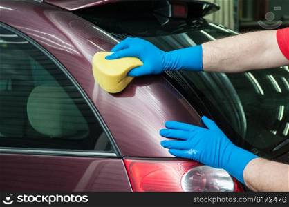 washing car with sponge. hand with sponge over the car for washing