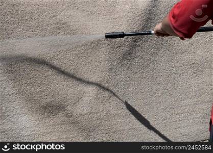 Washing carpets with high pressure washer. Cleaning the carpet with a gun for washing high pressure water
