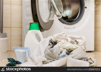 Washing powder detergent and measuring cup next to machine in bathroom. Household duties, clothes laundry obejcts concept.. Laundry washing powder detergent