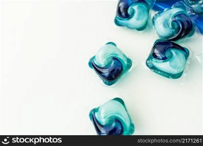 Washing powders in multi-colored capsules on a white background. The concept of washing and cleanliness. Washing powders in multi-colored capsules on a white background. The concept of washing and cleanliness.