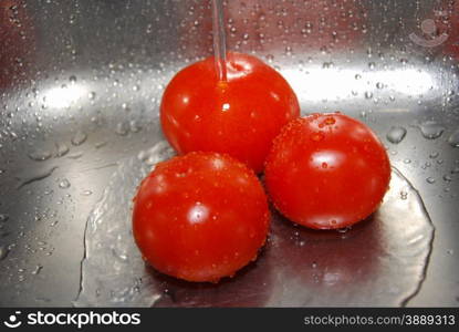 Washing tomatoes at streaming water in a kitchen