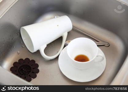 Washing up. White coffee cups in the kitchen sink.