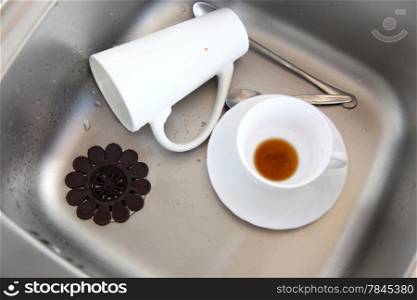 Washing up. White coffee cups in the kitchen sink.