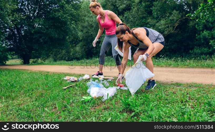 Waste pile and two girls running with bags doing plogging outdoors. Waste pile and two girls doing plogging