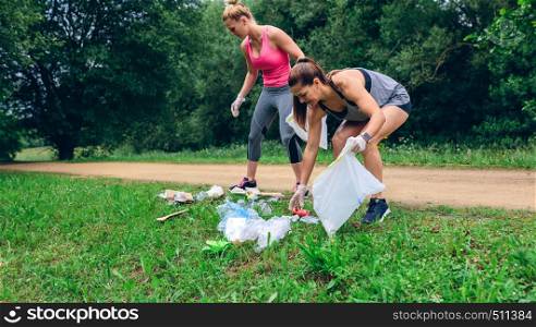 Waste pile and two girls running with bags doing plogging outdoors. Waste pile and two girls doing plogging