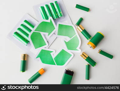 waste recycling, garbage disposal, environment and ecology concept - close up of used alkaline batteries and green recycling symbol