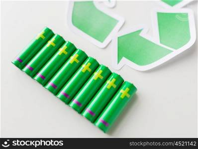 waste recycling, garbage disposal, environment and ecology concept - close up of used alkaline batteries and green recycling symbol