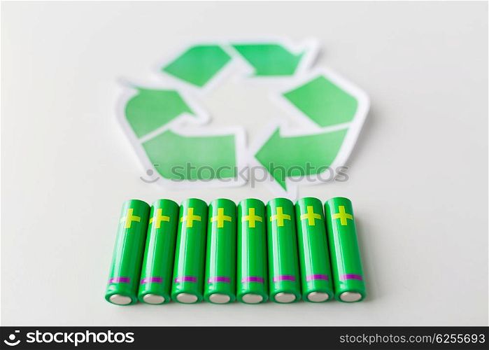 waste recycling, garbage disposal, environment and ecology concept - close up of used alkaline batteries and green recycling symbol