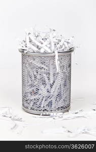 Wastepaper basket with papers lying around over white background