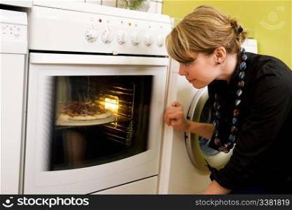 Watching a homemade Italia style pizza bake in the oven in an apartment kitchen;
