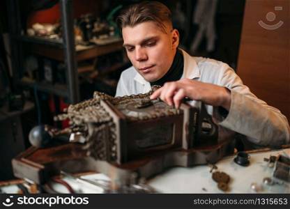 Watchmaker adjusts the mechanism of old wall clock in the workshop.. Watchmaker adjusts the mechanism of old wall clock