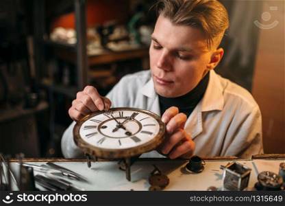 Watchmaker adjusts the mechanism of old watches in the workshop. Clock maker at work. Watchmaker adjusts the mechanism of old watches