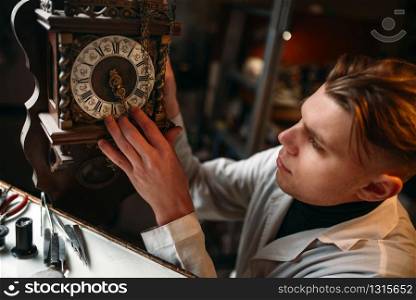 Watchmaker adjusts the mechanism of old watches in the workshop. Clock maker at work. Watchmaker adjusts the mechanism of old watches
