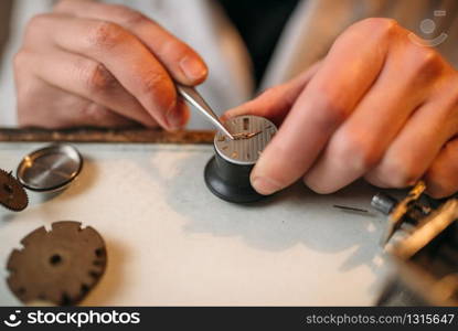 Watchmaker repair broken clockwork mechanism with small tweezers, macro view. Watchmaker repair broken clockwork with tweezers