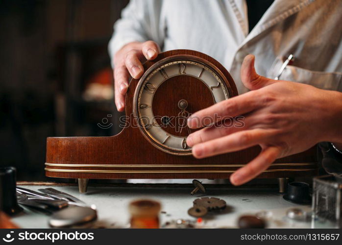 Watchmaker restore old wooden table clock. Clock maker at work