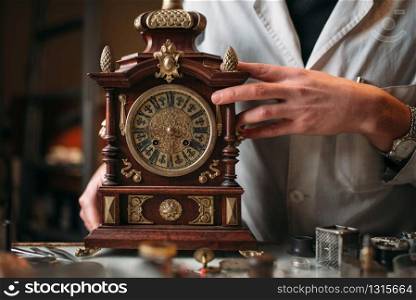 Watchmaker with old mechanical desk clock. Hour workshop. Watchmaker with old mechanical desk clock